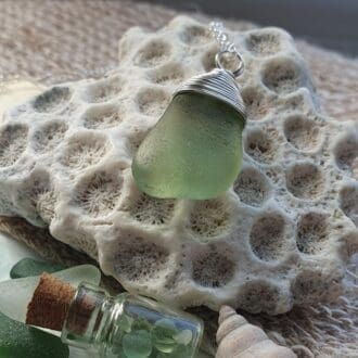 seafoam green seaglass bean with a wire-wrapped top sitting on top of a fossil coral