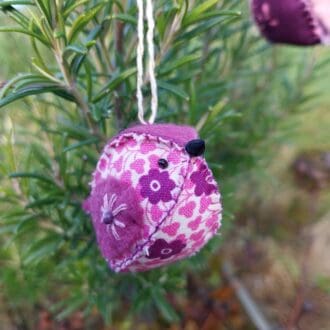 a handstitched felt and fabric bird decoration in shades of pink and purple.
