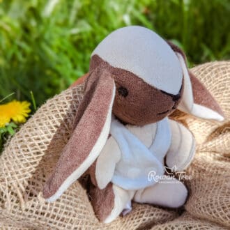 Handmade chocolate and cream furred velveteen bunny wearing light blue velveteen double breasted waistcoat sat on hessian on grass