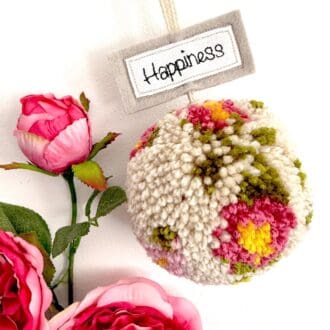 Beautiful pink and cream floral design wool pom pom hanging decoration with a free motion happiness stitched message