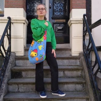 woman in green top holding large blue tote bag