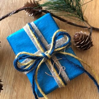 Arvor and Mor jewellery gift wrapped in sustainable peacock blue tissue paper with blue and ochre twine and a handmade copper ‘A’.