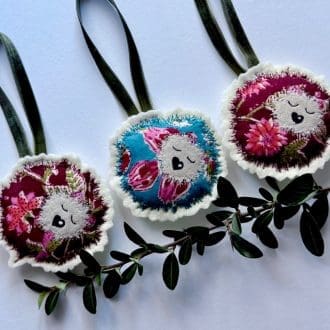 Handcrafted textile applique hanging hedgehog decoration. Backed with cream wool felt and hung with a green velvet ribbon. Light filled with polyfill