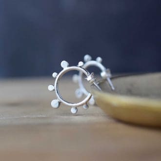 silver hoop earrings with dot design rest on a brass dish