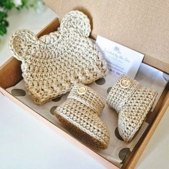 crochet baby teddy bear beanie hat and matching booties set, shown in Parchment in a cardboard box